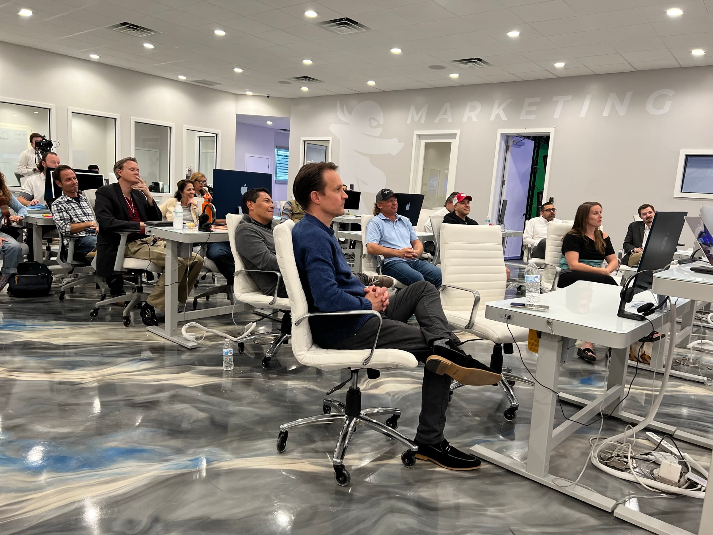 Workshop attendees and AGM staff working at rows of desks on the agency floor in Largo, Florida
